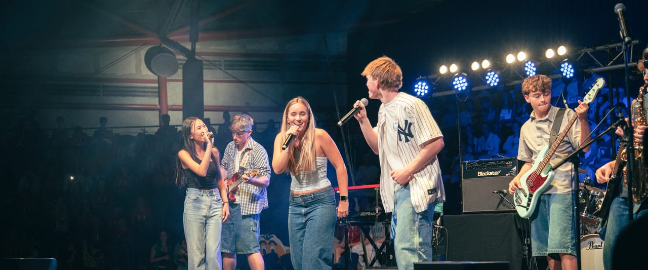 Singers and guitarists perform together on a concert stage.