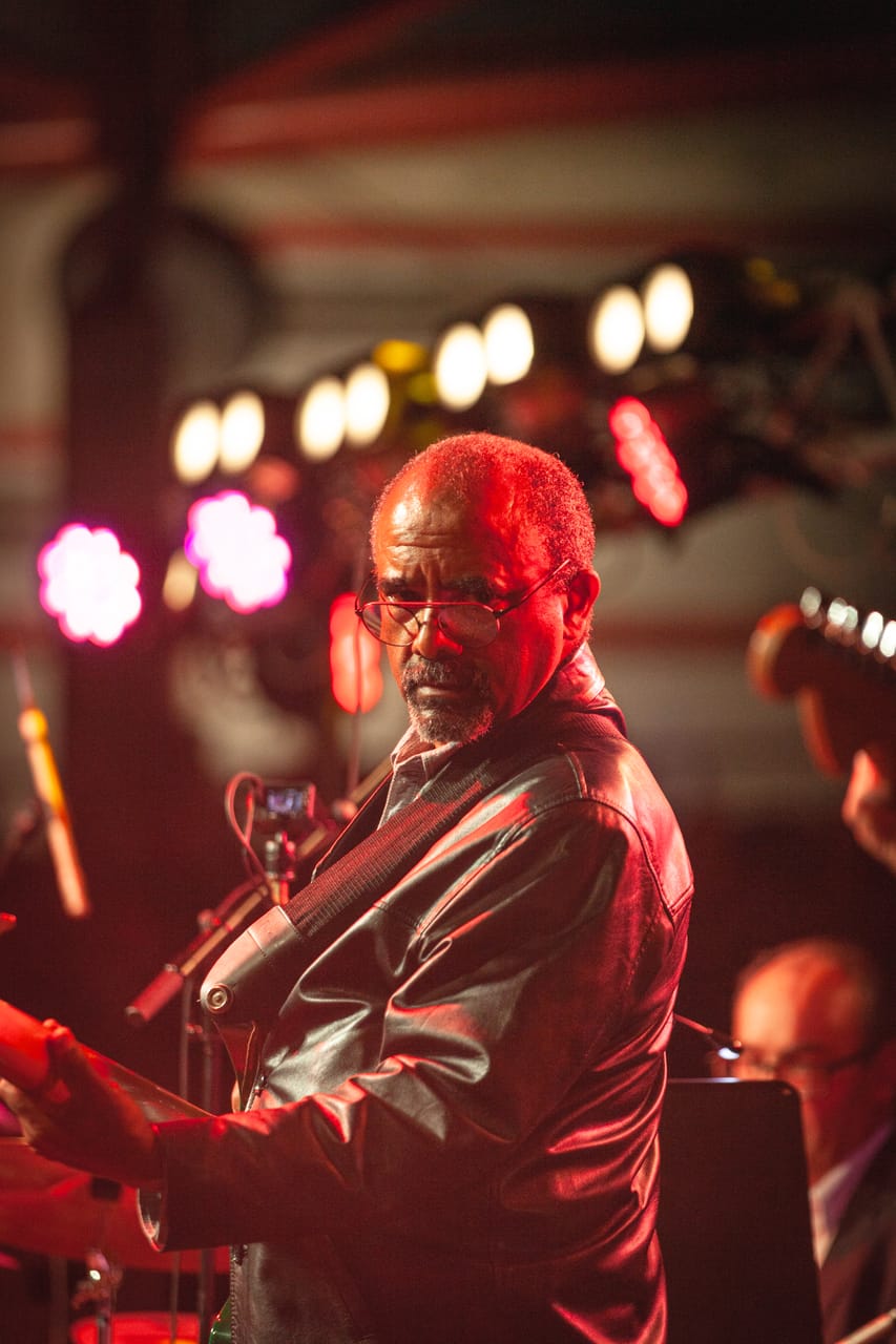 A guitarist plays under warm stage lights.