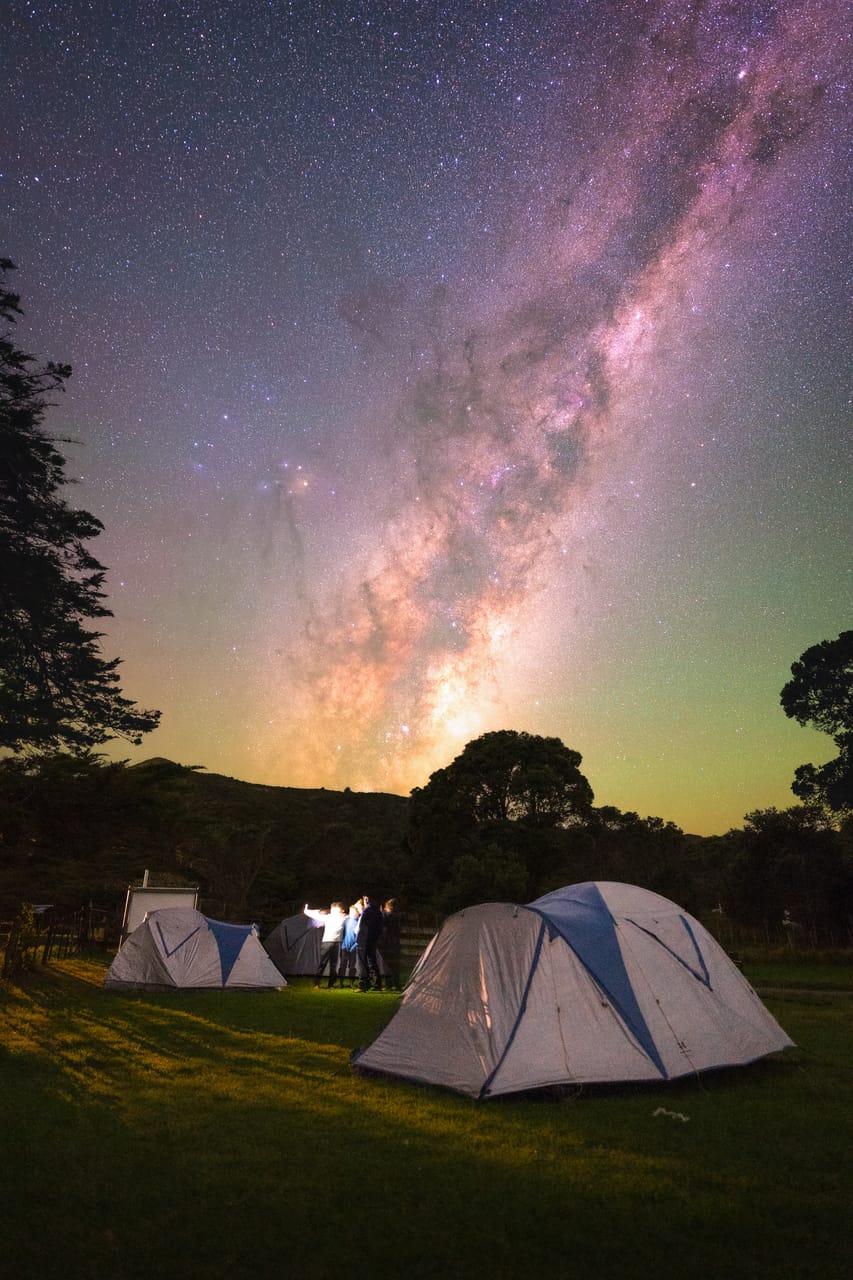 Tents pitched beneath the Milky Way at a campsite.