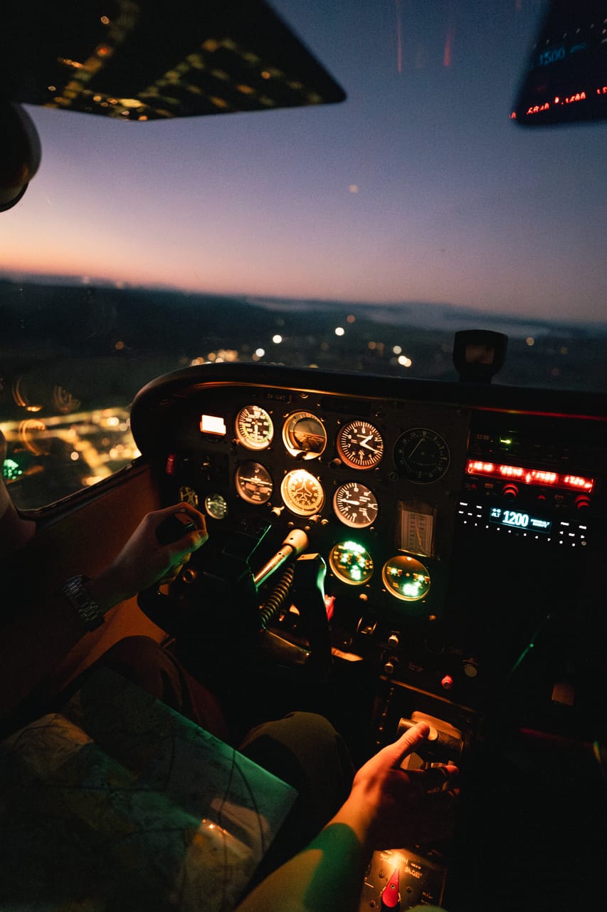 A pilot's view of cockpit instruments at dusk above city lights.