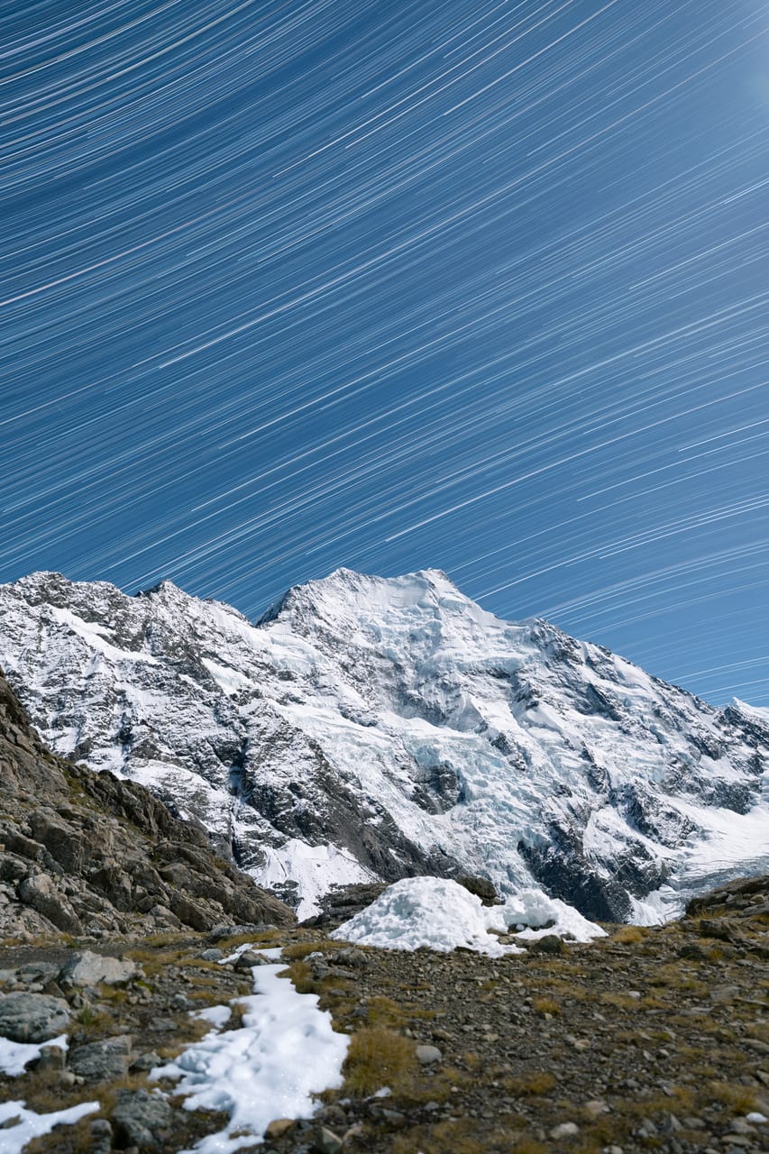 Star trails circle above a snow-covered peak.