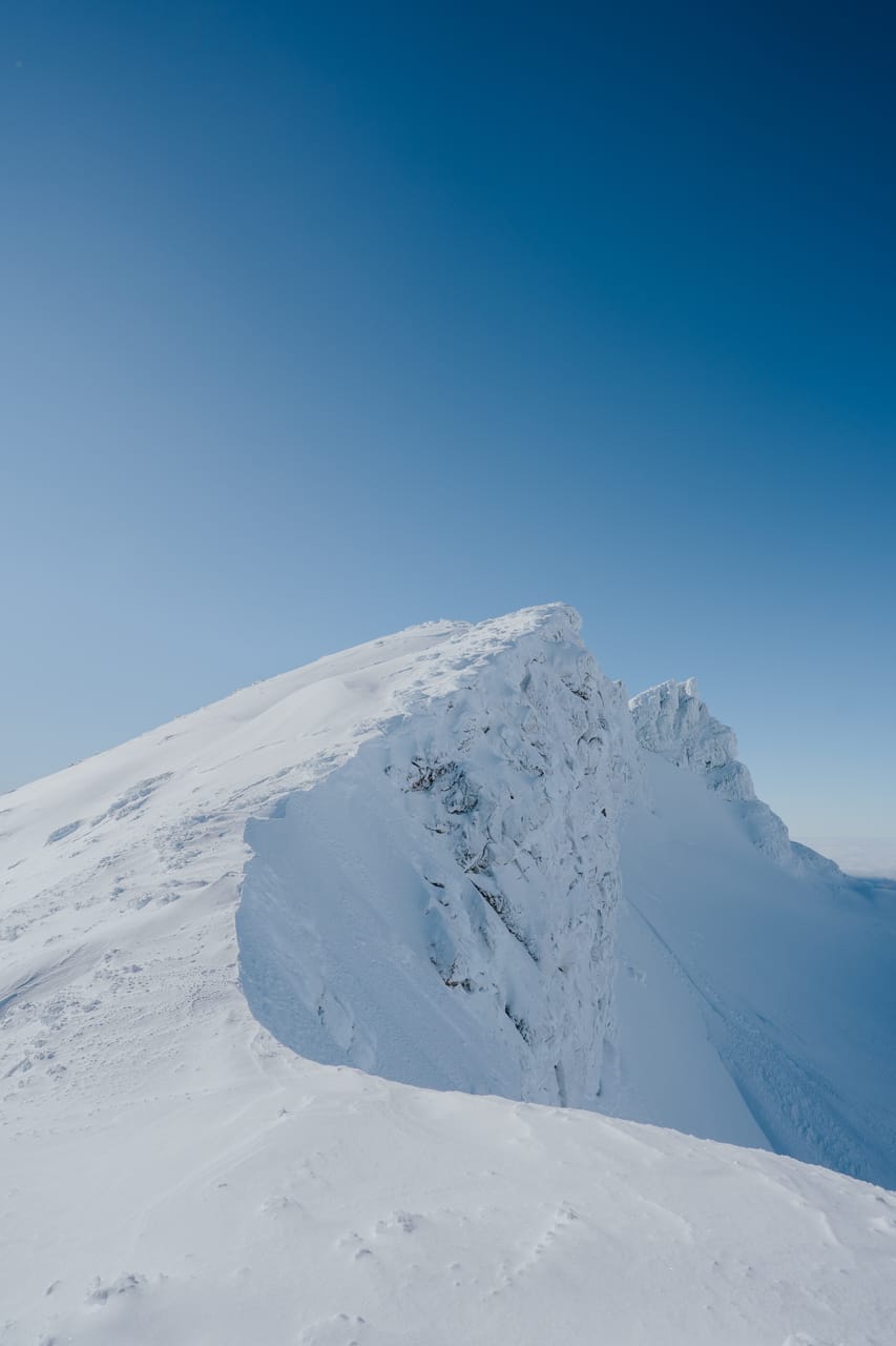 A snow-covered ridge against a deep blue sky.