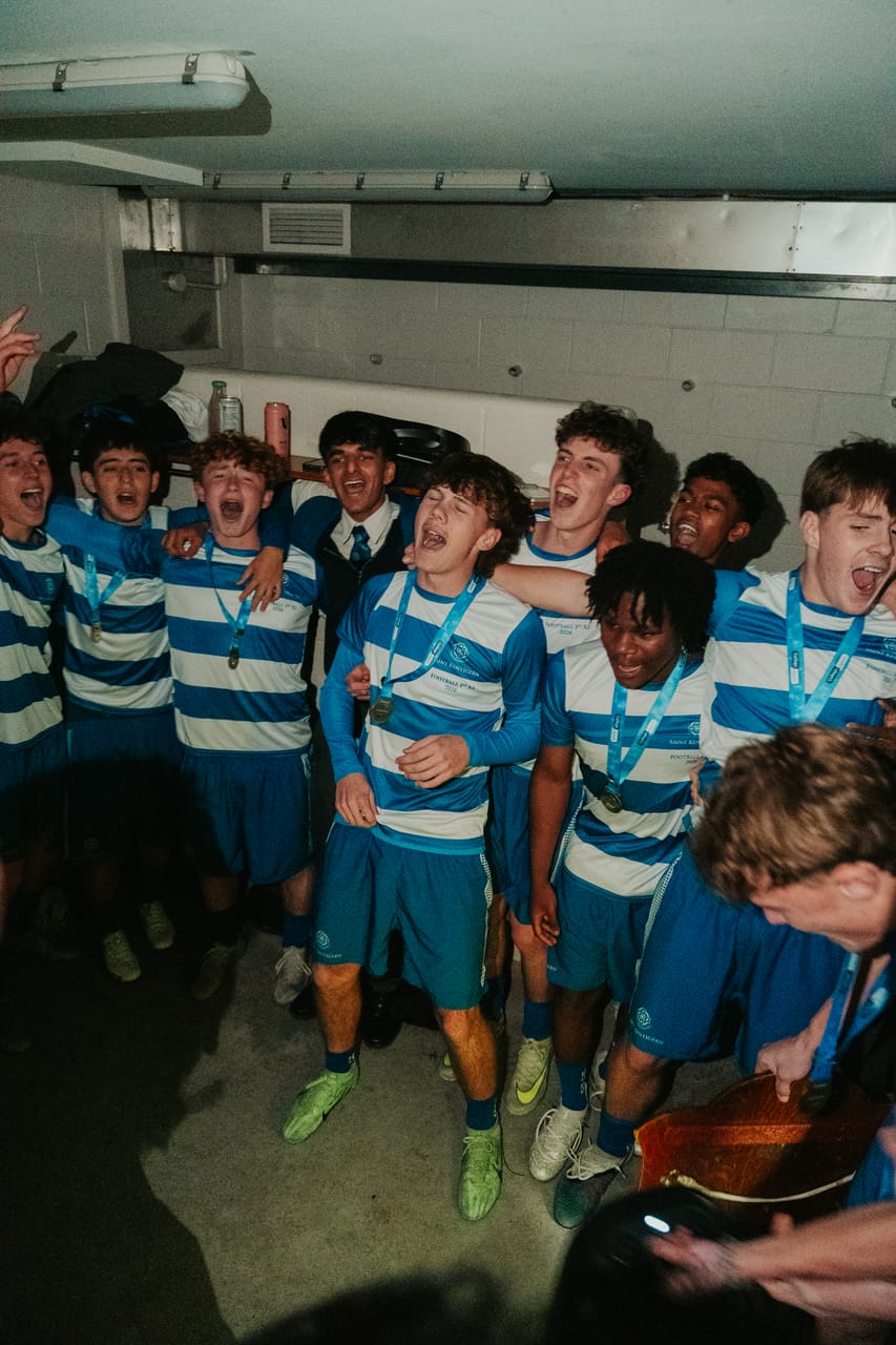 A team in blue-and-white stripes celebrates with medals in the changing room.