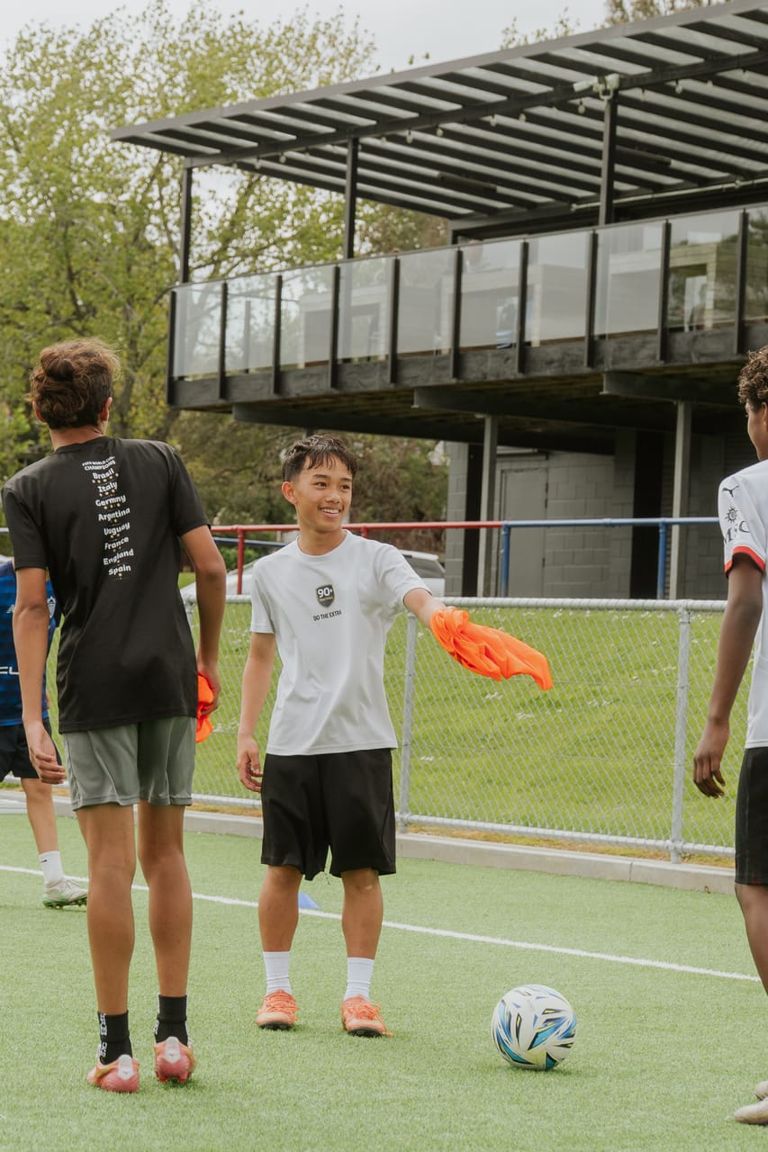 A coach gives instructions to a player during a daytime training session.