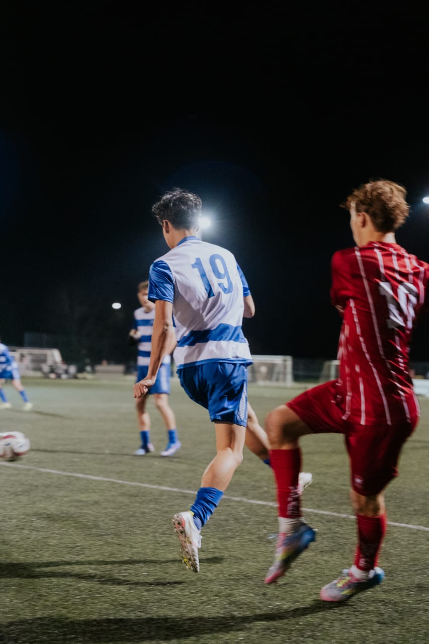 A player wearing number 10 dribbles away from a defender in red.